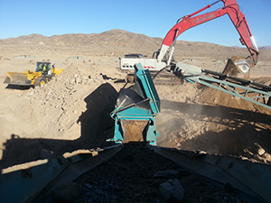 Excavator feeding construction material processing equipment